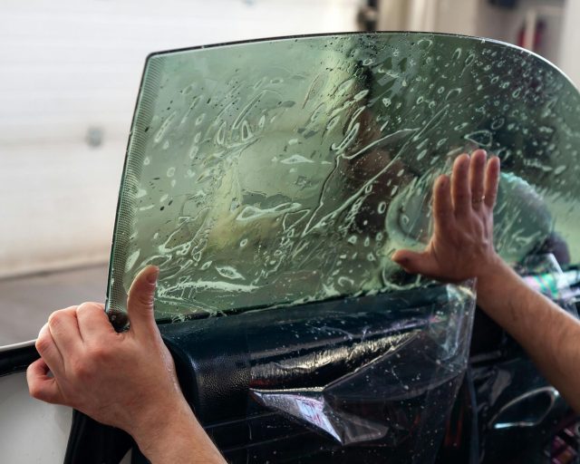 Technician installing protective film on a new car window at Quad Axis Global in Riyadh